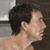 Pixelated close-up of a person's head and shoulder in profile, showing dark hair and light skin against a blurred background.