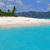A four- beach scene with turquoise water, sandy shore, footprints, and 'LOVE' written in sand under a blue sky