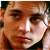 Pixelated close-up of a person's face with warm brown and orange tones, showing eyes, nose, and mouth in a static composition.