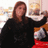 A pixelated image shows a person with long brown hair wearing a black top, holding an object with red and white colors against a blurred background.