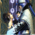 Pixelated static image of two figures in formal attire with a blurred background featuring circular light patterns.