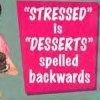 A static image shows a bright pink rectangular sign with white text reading "STRESSED" is "DESSERTS" spelled backwards against a teal background.