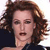 Pixelated close-up of a person with curly brown hair wearing a dark blue top against a white background.