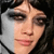 Pixelated close-up of a person's face with dark hair, showing eyes, nose, and mouth against a dark background.