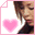 Pixelated image of a person with brown hair and dark clothing, holding a pink heart-shaped object that changes from empty to displaying 'E' in white text.