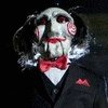 Static image of a character with a pale, stitched face, red lips, and a red bow tie against a dark background.