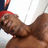 A pixelated close-up of a person with brown skin wearing a red headband and dark clothing, set against a bright background.