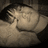 Pixelated grayscale image of a person with closed eyes and hand near face, next to vertical pink text on black background.