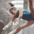 Pixelated static image of a gymnast performing on uneven bars with visible motion blur and grayscale background.
