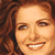 A pixelated close-up of a person with light brown hair and fair skin smiling, showing teeth.