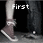 Two pairs of legs in dark pants and brown sneakers with white soles, one pair stepping forward with text 'First' and the other with 'Kiss' above them.