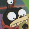 A cartoon character with large white eyes, black pupils, and a long beige beak-like nose with visible teeth, wearing a red garment against a blurred background.