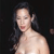 Pixelated image of a person with long dark hair, light skin, and red lips against a dark background.