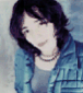 A person with short dark hair wears a blue plaid shirt over a gray top and necklace, shown in six with varying lighting and color tones