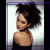 A woman with dark hair styled in a high messy bun, wearing a black halter top, shown from the shoulders up against a light background.