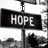Black rectangular sign with white pixelated text reading HOPE, mounted on a vertical pole against a light background.
