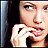 Pixelated close-up of a person with light skin wearing white clothing, holding an object near their mouth against a dark background.