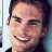 A pixelated image shows a person with short dark hair and light skin smiling, next to green text on a dark background.
