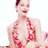 Static pixelated image of a person in red lingerie with dark hair, visible tattoos on arms and chest, closed eyes, and a slight smile against white background.
