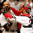 Pixelated image of a person in red and white clothing holding an object, with visible facial features and dark hair.
