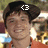 Pixelated image of a person in an orange shirt with dark hair, featuring text overlays and a blurred background.