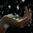 A pixelated hand with a raised index finger against a dark background scattered with light speckles.