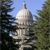 Pixelated image of a domed building with a spire, framed by trees against a blue sky, rendered in low-resolution style.