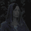 A pixelated figure with long dark hair wears a blue hooded garment against a dark background, with visible motion in the head and shoulder area.