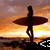 Silhouette of a figure with outstretched arms against an orange and yellow sunset sky, standing on dark ground.