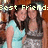 Two people embrace under pixelated text reading 'Best Friend:' with one in a light blue sleeveless top and the other in a dark gray sleeveless top against a brown background.