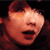 Pixelated close-up of a face with closed eyes, open mouth, and reddish-brown hair against a dark background.