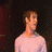 A static image of a person in a pink long-sleeve shirt against a dark background, with visible pixelation and low resolution.