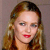 A pixelated close-up of a person with light brown hair, red lips, and a neutral expression against a muted gray background.