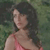 Pixelated image of a person with dark hair wearing a pink sleeveless top against a greenish background.