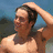 A shirtless man with dark hair stands outdoors, hand on head; text overlays change