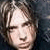 Pixelated close-up of a person's face with light skin tone, dark hair, and closed eyes against a dark background.