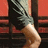 A person's lower legs and feet in motion against a red background, wearing dark shorts with light stripes
