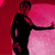 A pixelated figure in black clothing stands against a gradient background shifting from deep red to light pink, extending one arm horizontally.