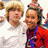 Two people in a pixelated image, one in white shirt, one in red with blue lanyard, both smiling against light background.
