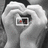 Two identical grayscale hands form a heart shape, each holding a small rectangular frame with red and black elements inside.