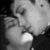 Black-and-white image of two people kissing, one with hand near face, the other with hand on shoulder.