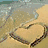 A beach scene with a heart drawn in sand, waves lapping at the shore, and green foliage with 'SUMMER' text.