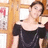 A pixelated image of a person in a black off-shoulder top against a wooden background with framed items.