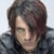 Pixelated close-up of a person with dark brown hair and light skin wearing a dark jacket against a pale background.