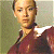 Pixelated portrait of a person with short light brown hair wearing a dark red collared shirt against a muted green background.