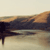 A static pixelated image shows a dark silhouette of a figure standing on a shore with a body of water reflecting the sky and distant landmass under a pale sky.