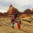 Pixelated landscape showing two figures walking across a field toward distant rock formations under a pale sky.