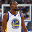 Pixelated static image of a basketball player wearing a white jersey with blue and yellow accents, standing in front of a blurred background featuring a basketball hoop.