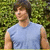 A person in a light blue sleeveless shirt stands against green foliage, with three distinct facial expressions