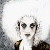 A pixelated figure with white hair and dark clothing holds a finger to lips against a bright background, next to green text reading 'Original Icons .com'.